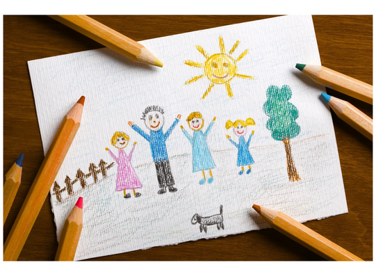 Colored pencil drawing of a family with two adults, two children, a dog, a tree, a sun, and a fence on white paper surrounded by colored pencils.