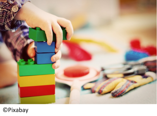 Bausteine Kinderhände bauen einen Turm mit bunten Bausteinen