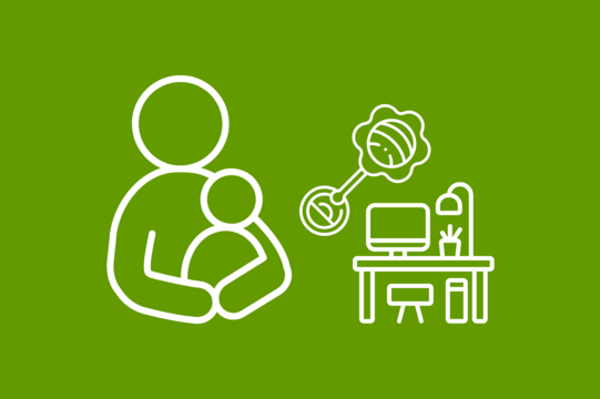A parent has a child in his arms, to the right is a desk and children's toys.