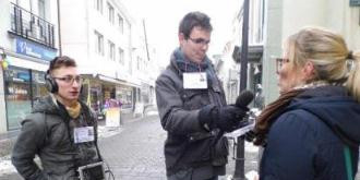 Drei Männer interviewen eine Frau auf der Straße