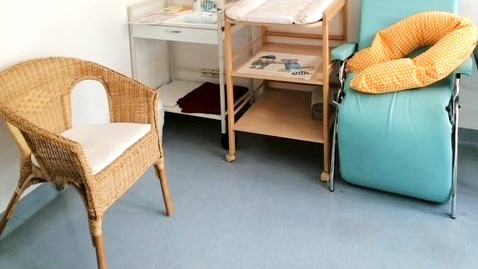 [Translate to English:] Kleine Sitzeecke mit einem Stillstuhl und einem Wickeltisch