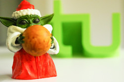 kleine Yodafigur in Weihnachtsoutfit vor TU-Logo