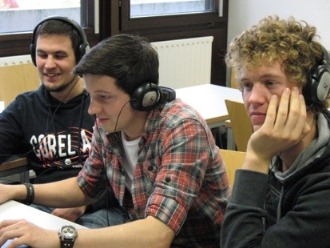 drei Männer mit Kopfhörern probieren etwas am PC aus