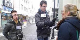 Drei Männer interviewen eine Frau auf der Straße