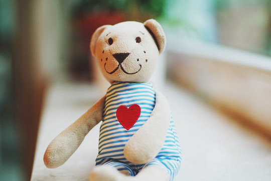 stuffed bear wearing a striped dress with a red heart printed on