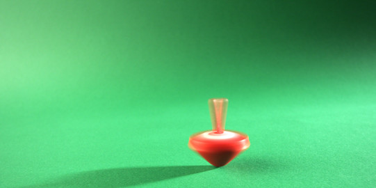 A red spinning top spins on a green bottom.